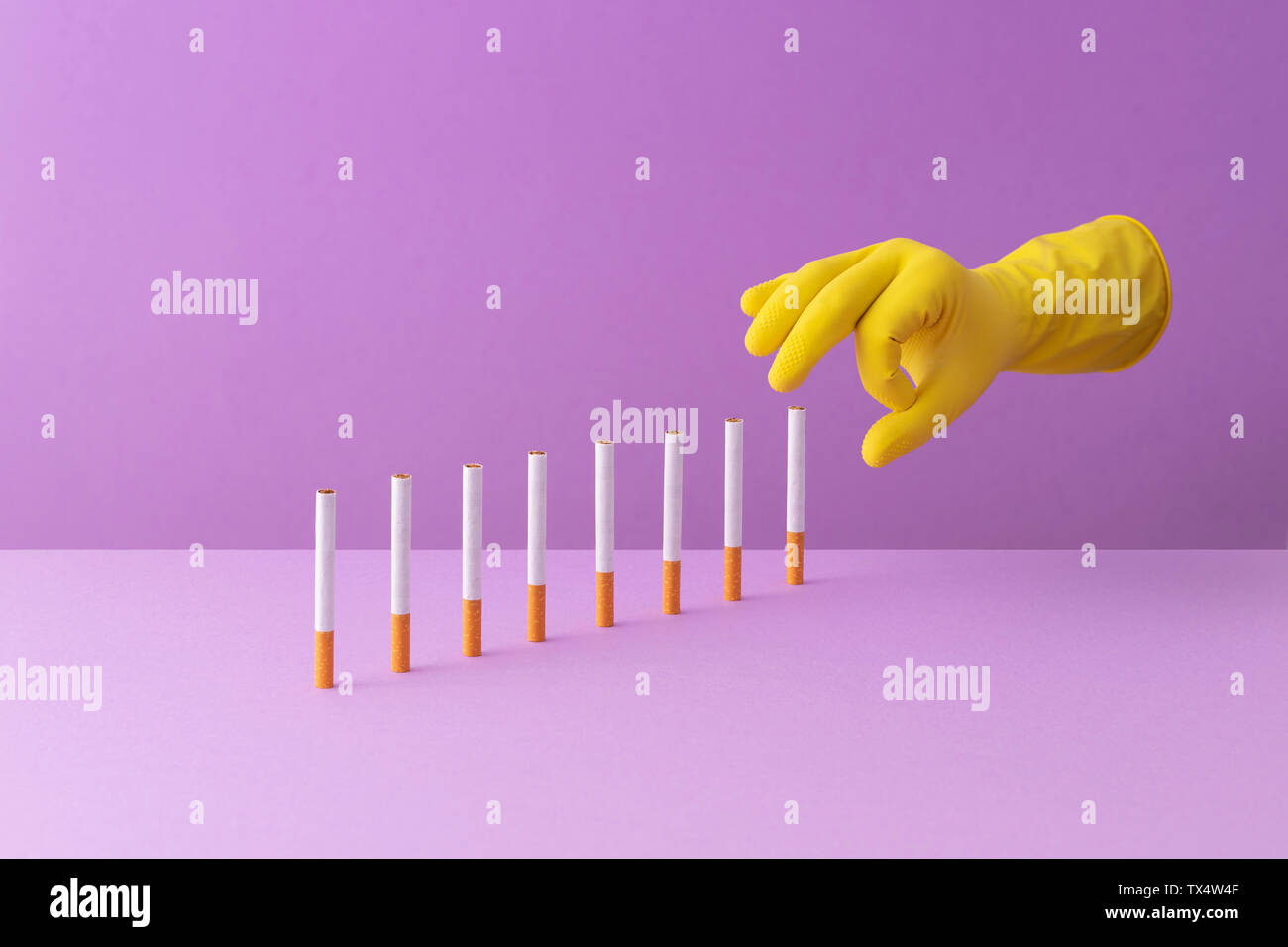 Hand shoving cigarettes in a row, creating a domino effect Stock Photo