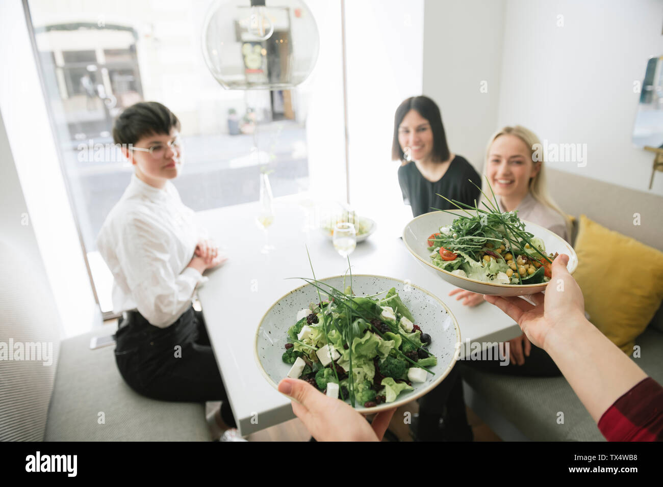 Waiter serving salad to friends in a restaurant Stock Photo