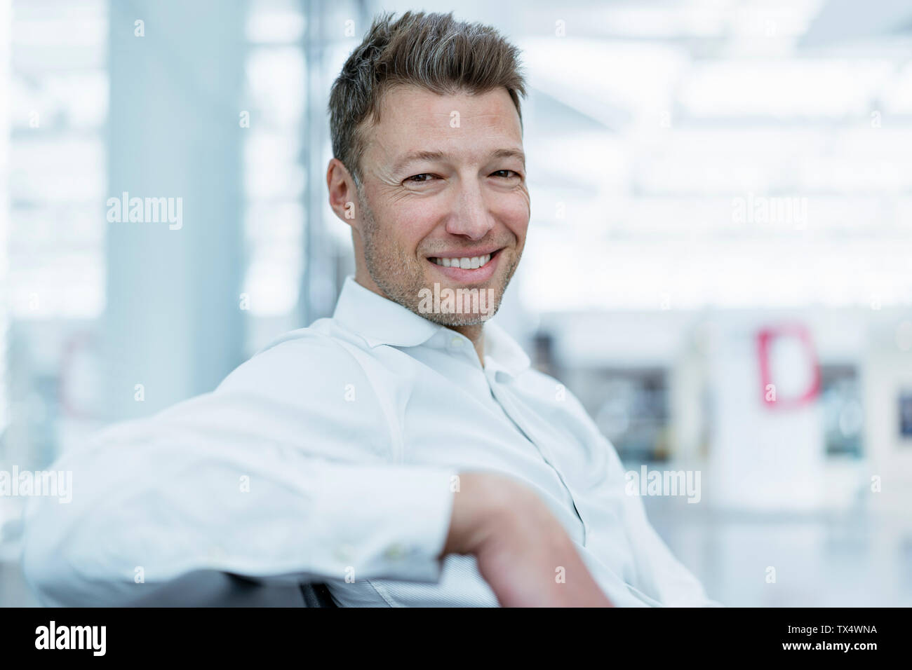 Portrait of smiling businessman sitting in waiting area Stock Photo