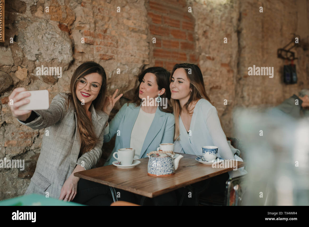 Three young women taking a selfie in a cafe Stock Photo - Alamy