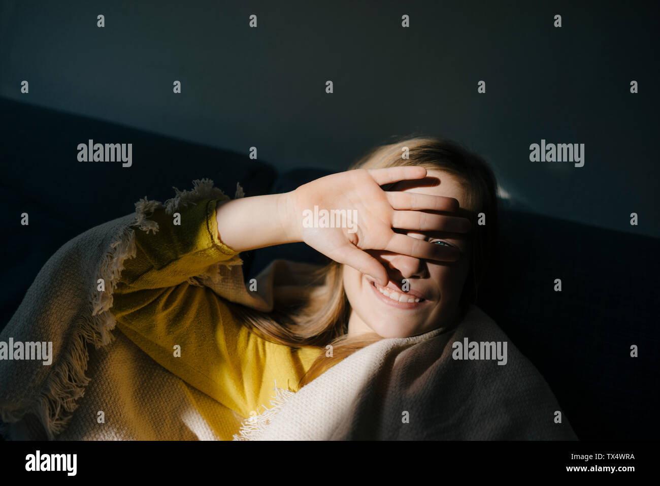 Girl at home shielding her eyes from sunshine Stock Photo