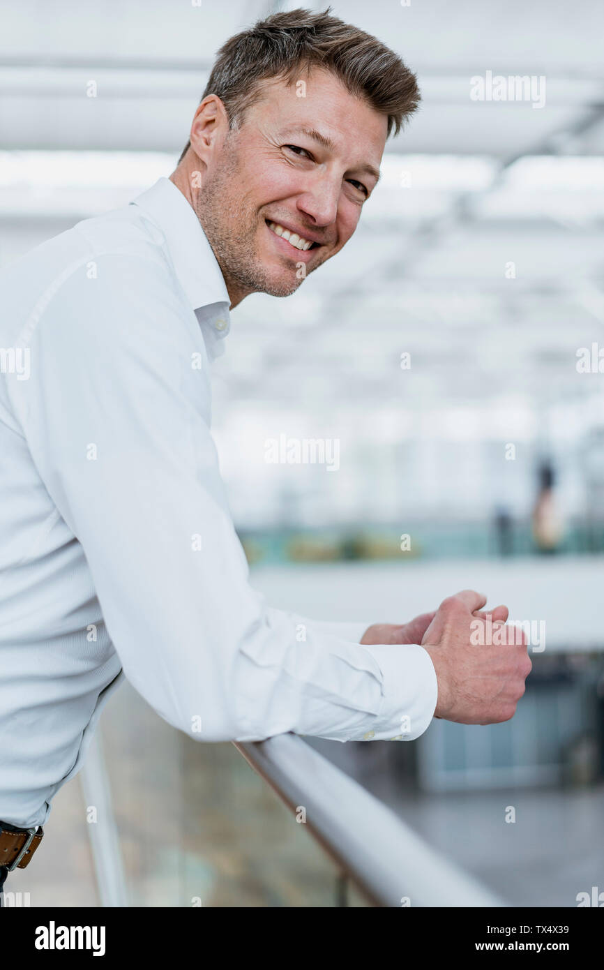 Portrait of smiling businessman leaning on railing Stock Photo