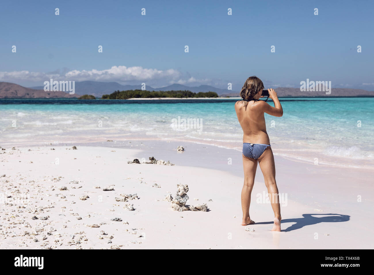 Indonesia, Komodo National Park, girl on beach taking a picture Stock Photo  - Alamy