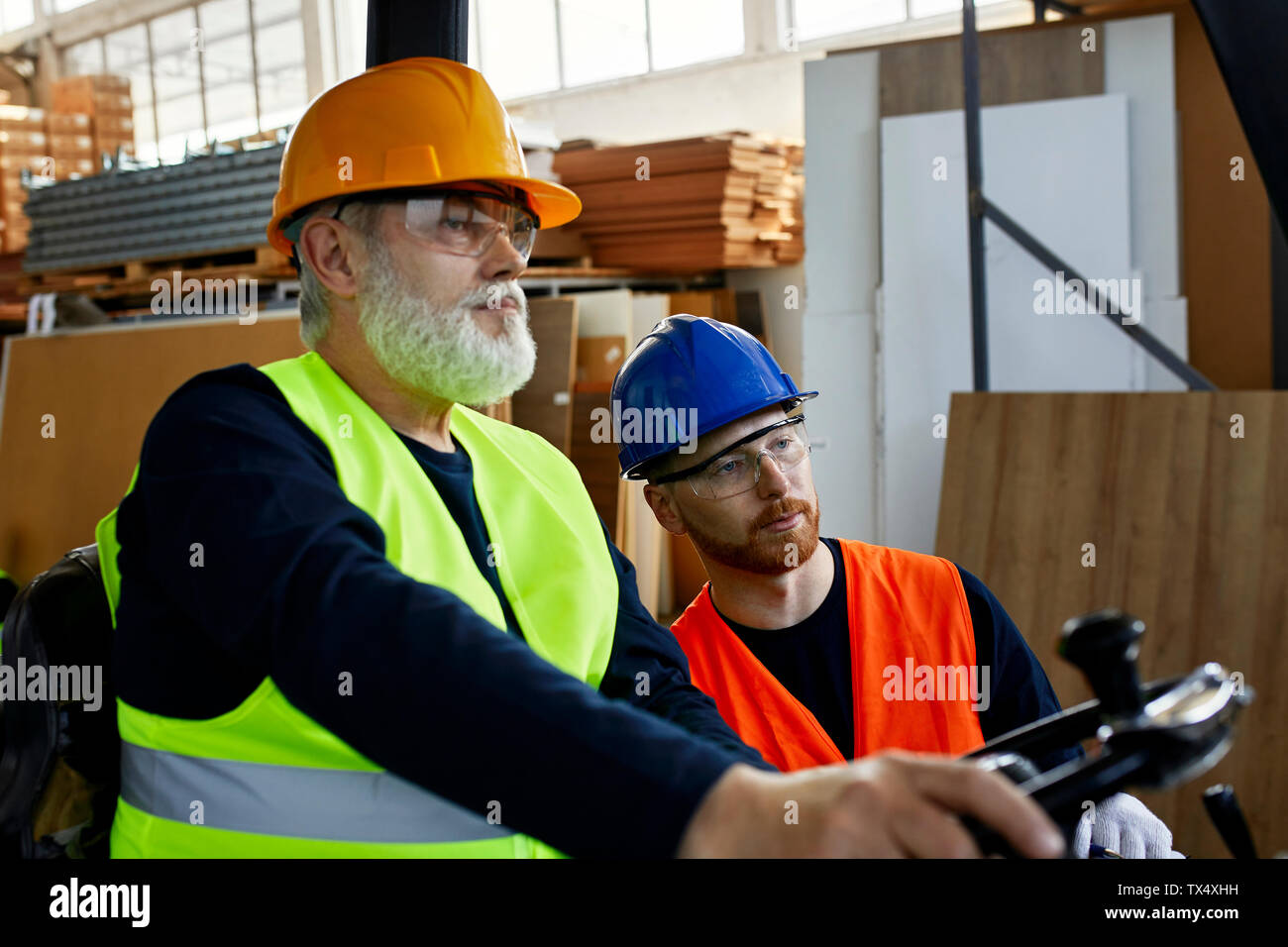 Two men with forklift in factory Stock Photo