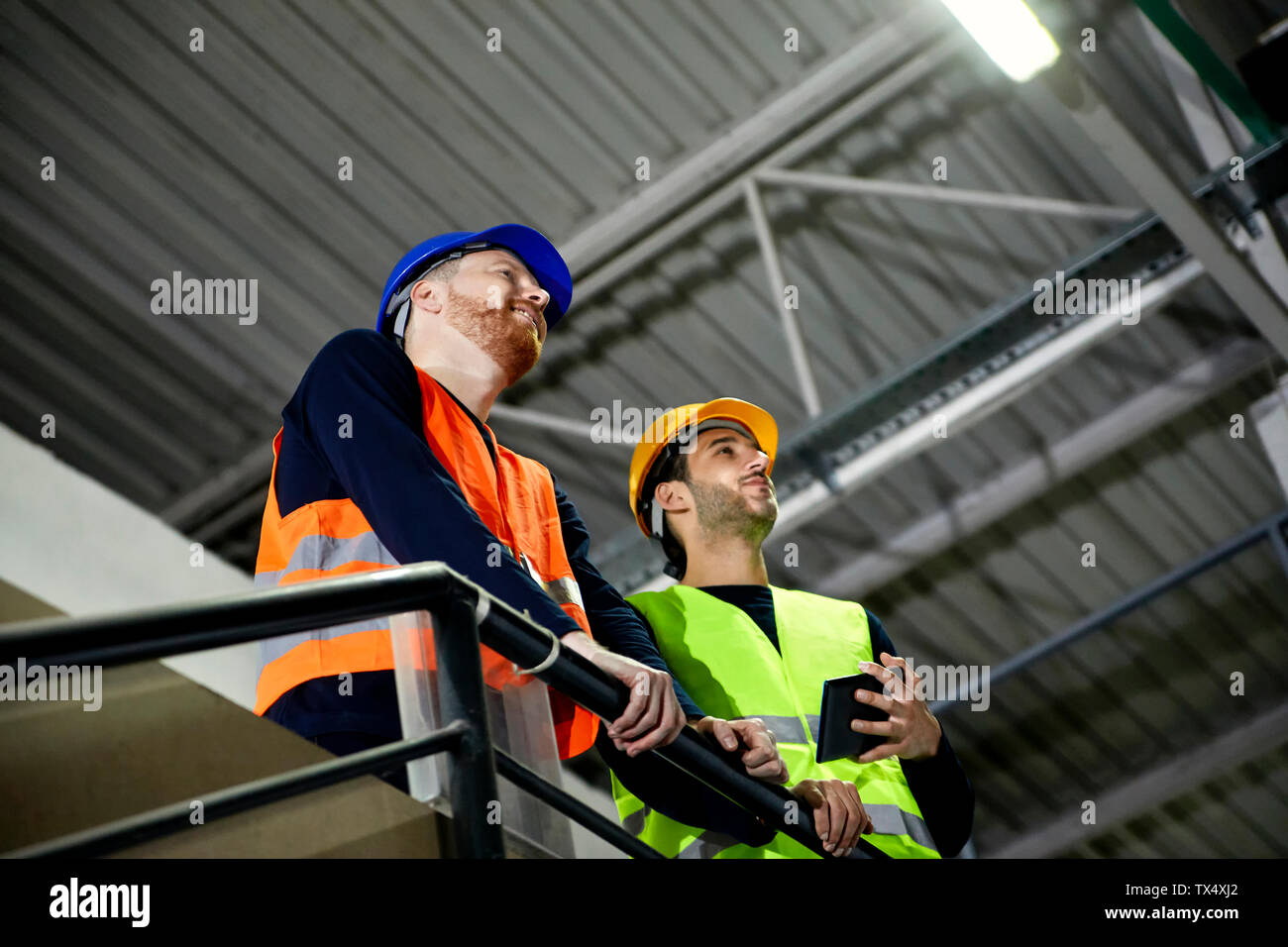 Two workers standing on upper floor in factory Stock Photo