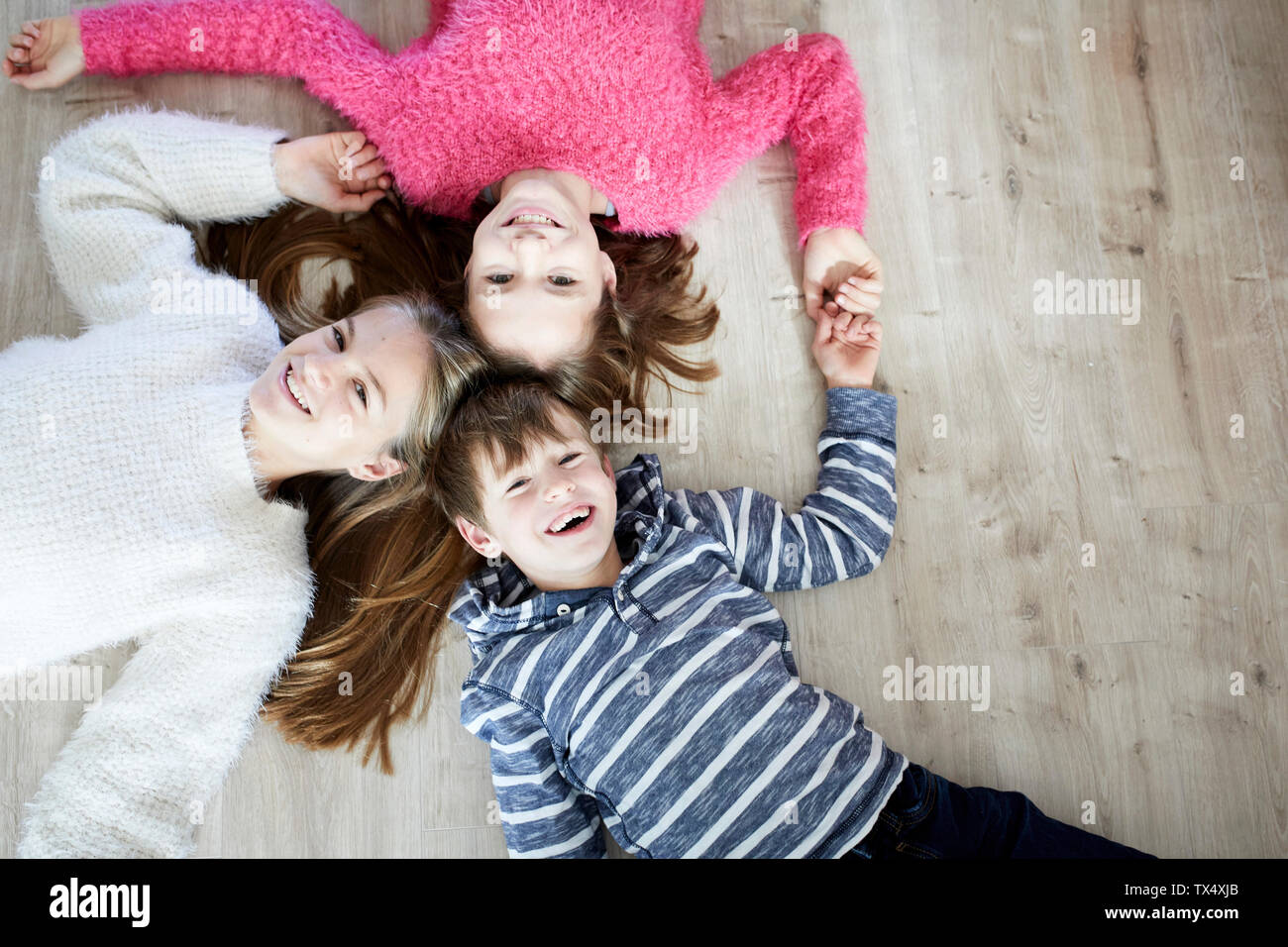Happy siblings lying on the floor, laughing Stock Photo