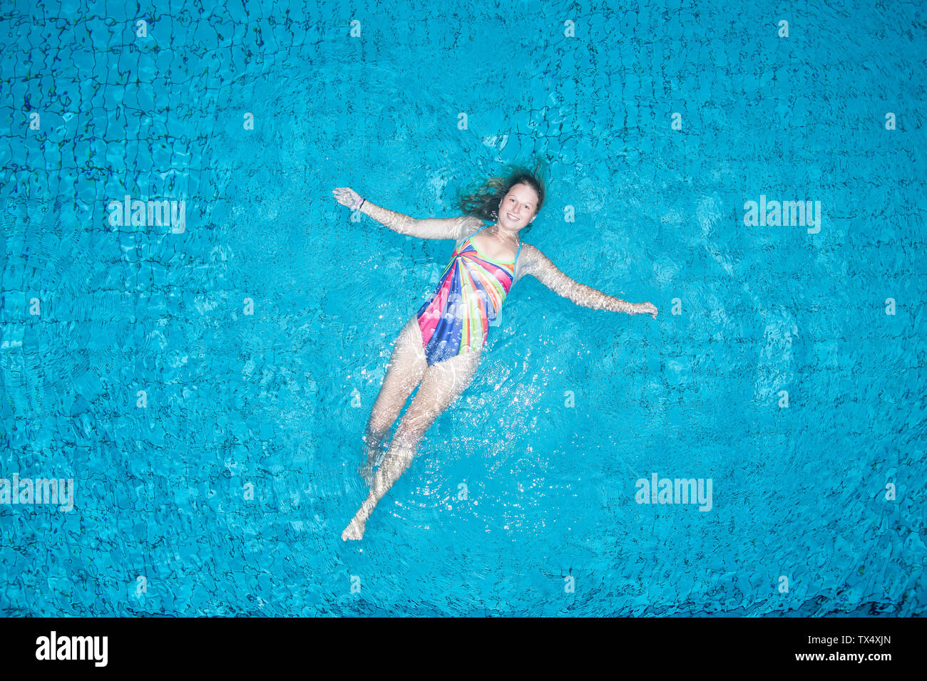 Young woman floating on water in swimming pool Stock Photo