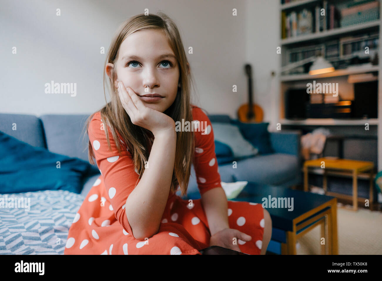 Portrait of serious girl sitting on couch at home Stock Photo