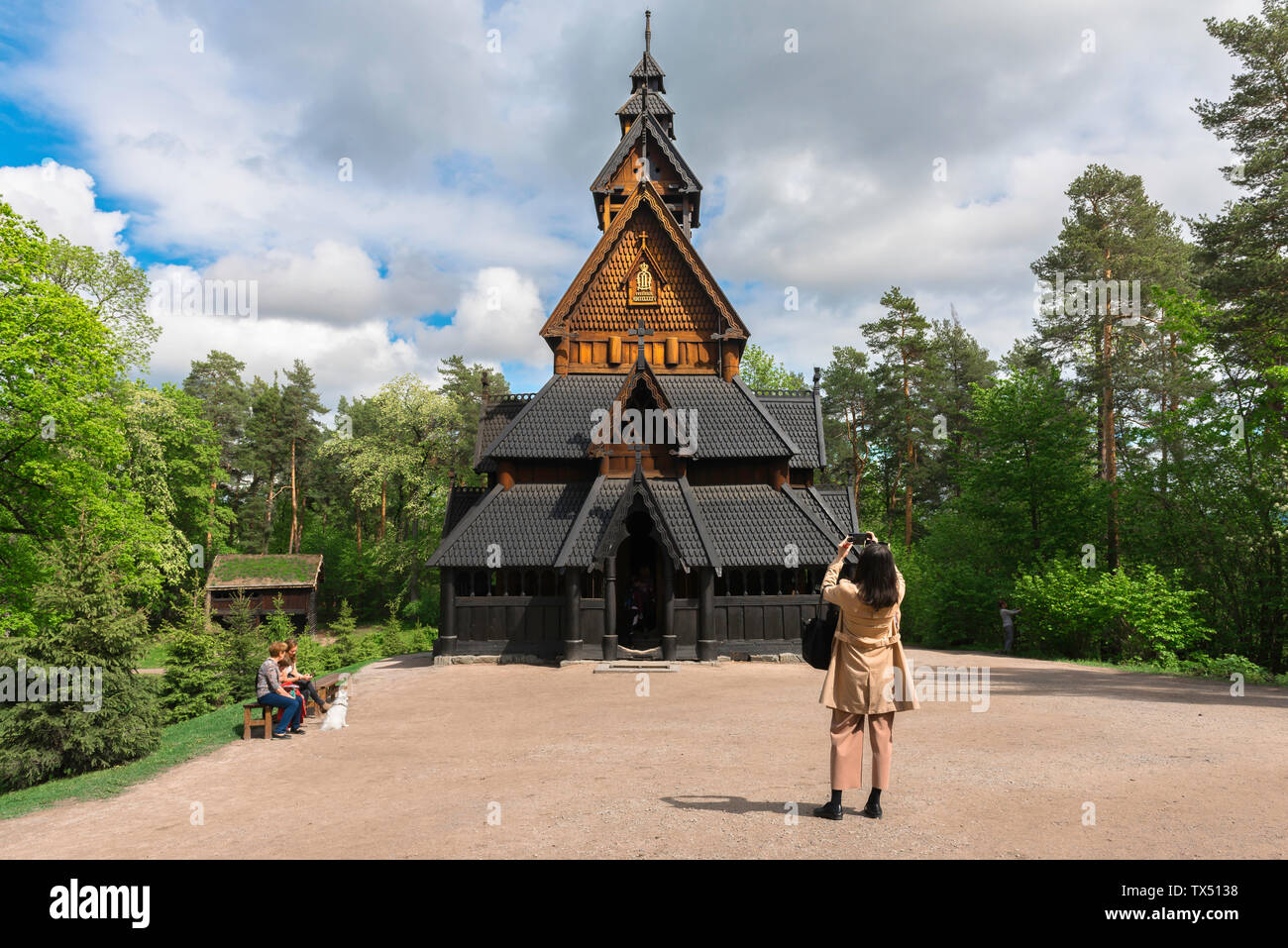 Norway Folk Museum, rear view of a female tourist taking a photo of a Norwegian stave church sited in the Norsk Folkemuseum in the Bygdøy area of Oslo. Stock Photo