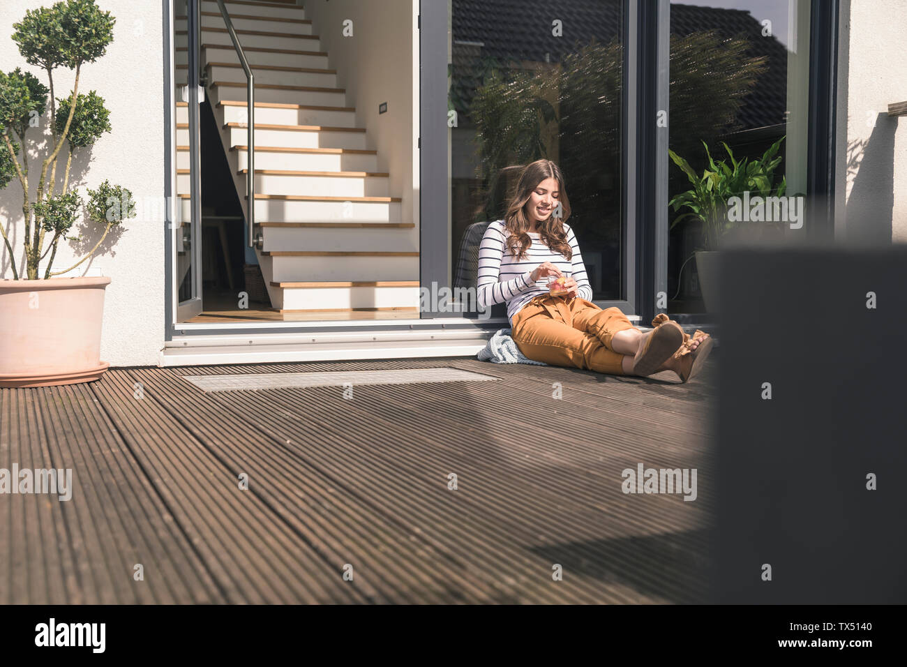 Young woman sitting on terrace at home Stock Photo - Alamy