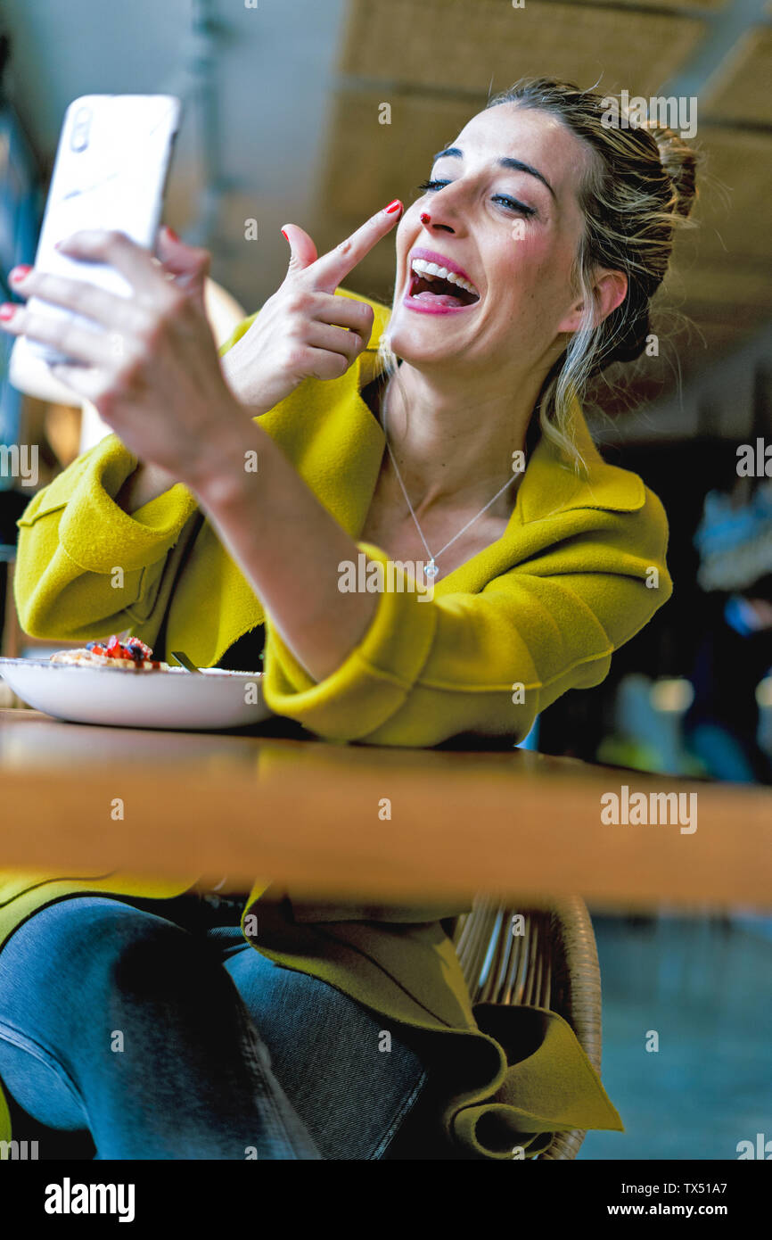 Happy playful woman taking a selfie in a cafe Stock Photo - Alamy