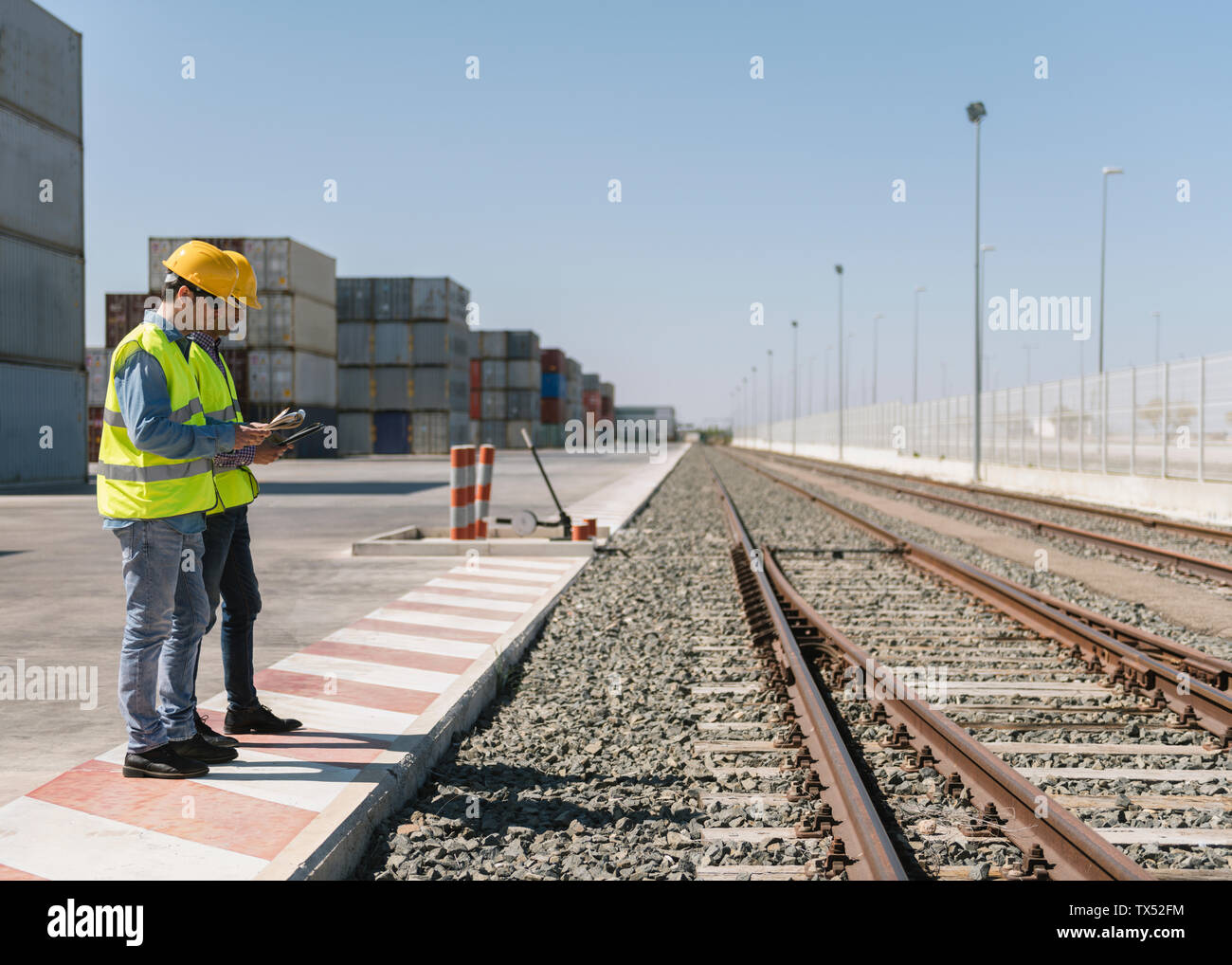 Workers in front of cargo containers near railway tracks on industrial ...