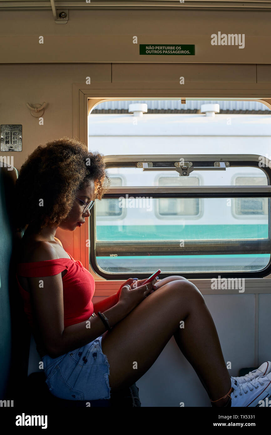 Young woman on a train checking her phone Stock Photo