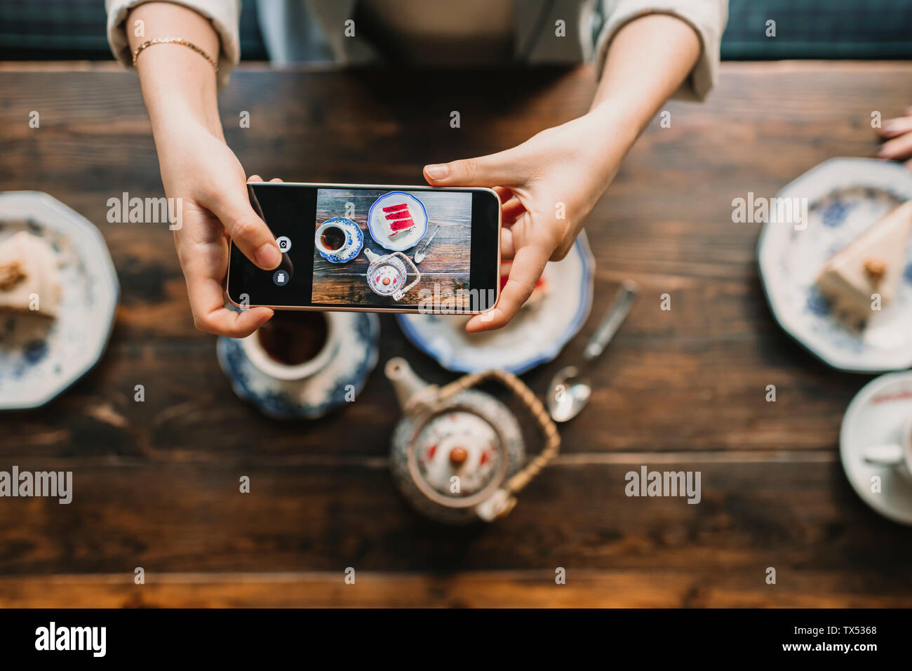 Top view of woman taking a photo of cake and tea in coffee shop Stock Photo