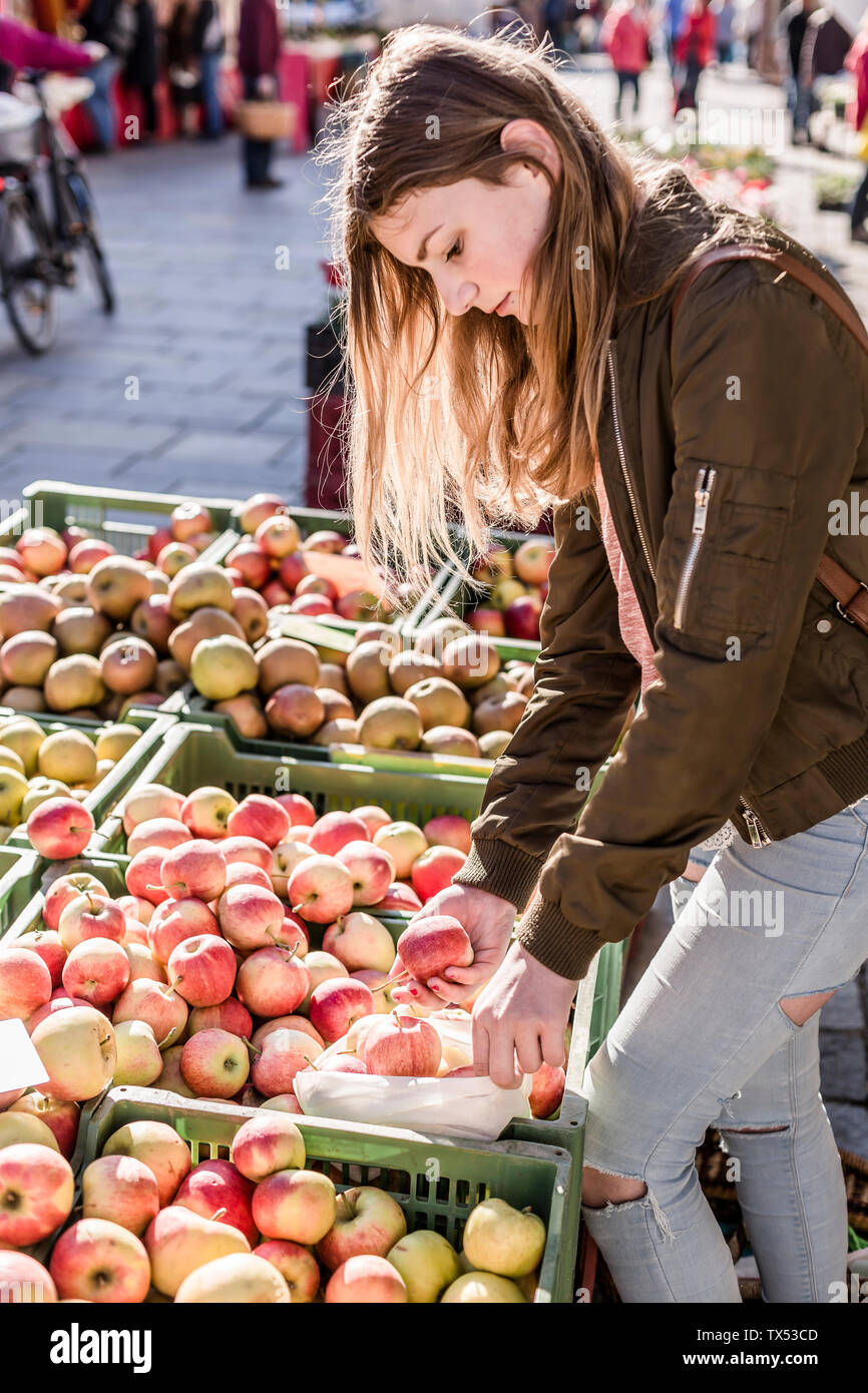 Girl with cloth bag choosing apples on weekly market Stock Photo