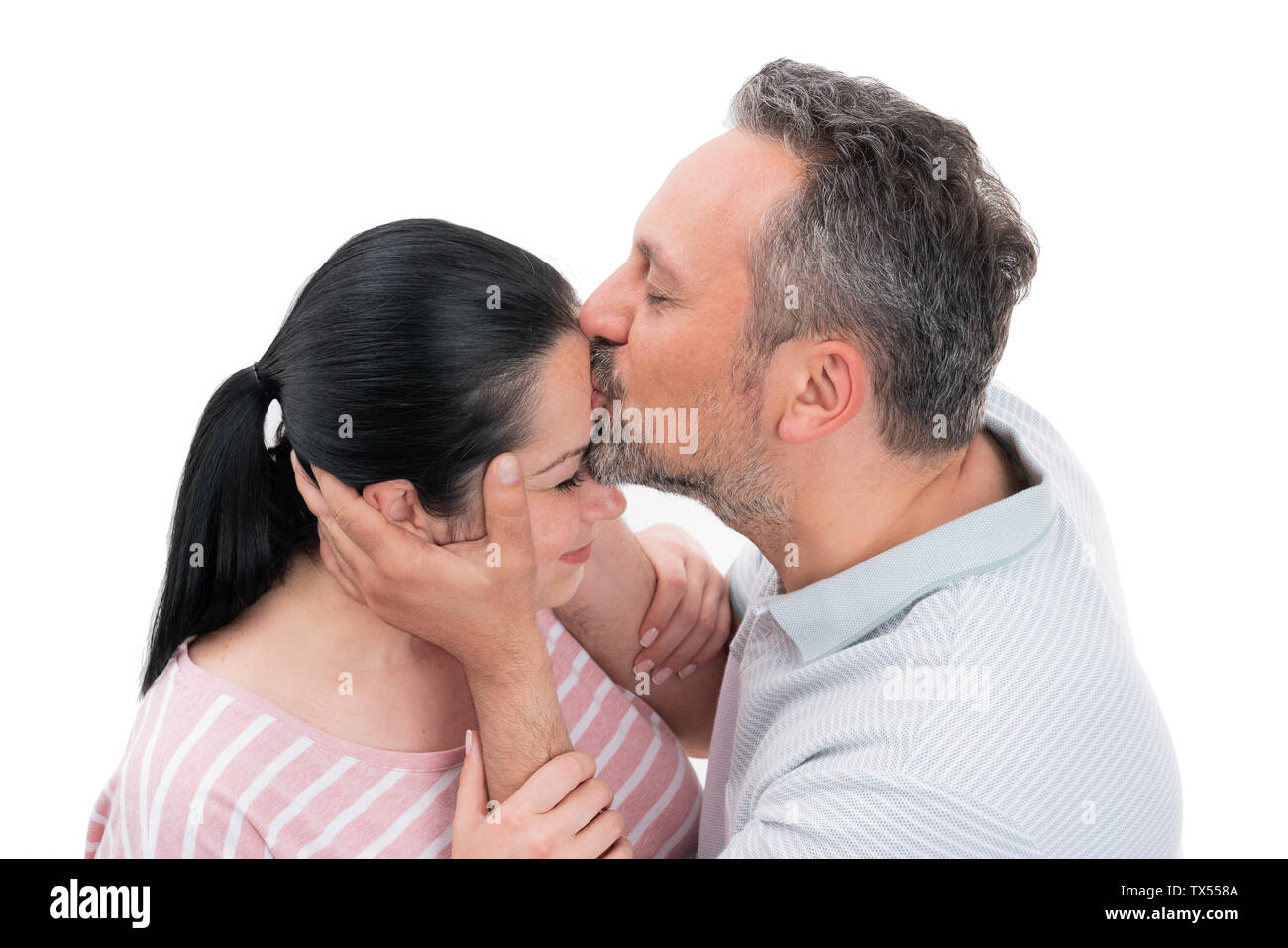 Loving man kissing forehead of smiling woman as cute relationship gesture isolated on white background Stock Photo