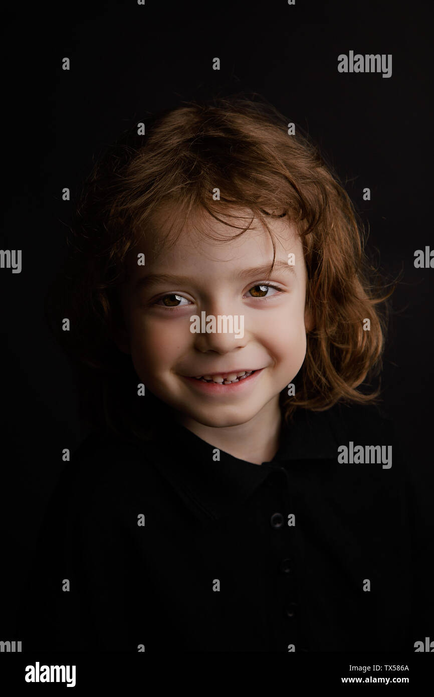 5 year old boy with long hair studio portrait on black background Stock Photo