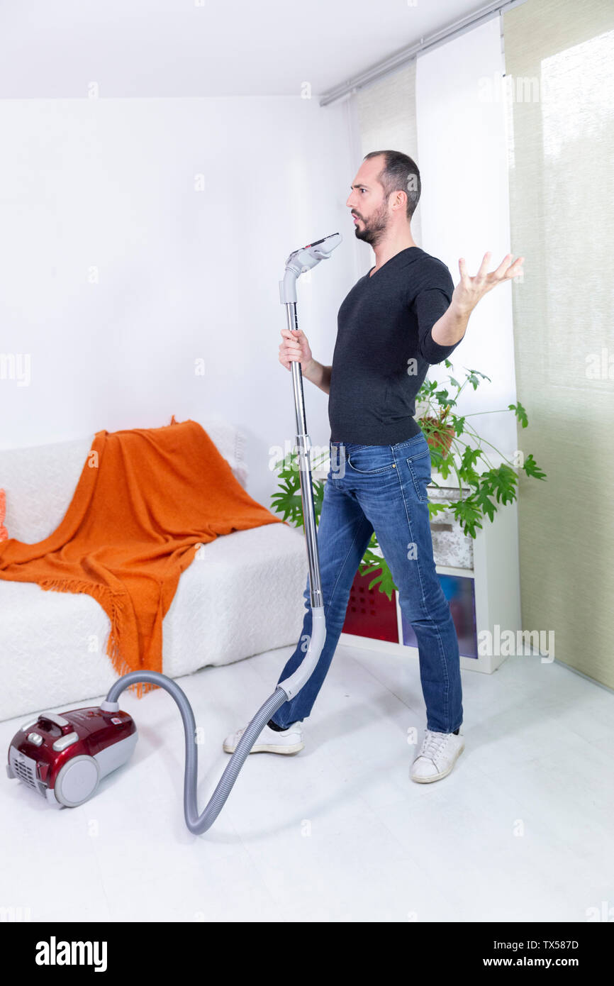 A man singing with a vacuum cleaner. Stock Photo