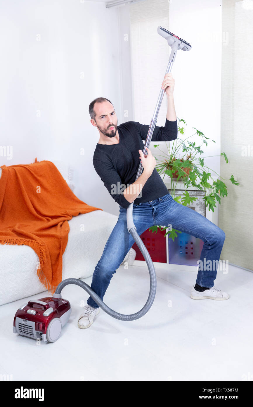 A man pretending to be a guitarist with a vacuum cleaner. Stock Photo
