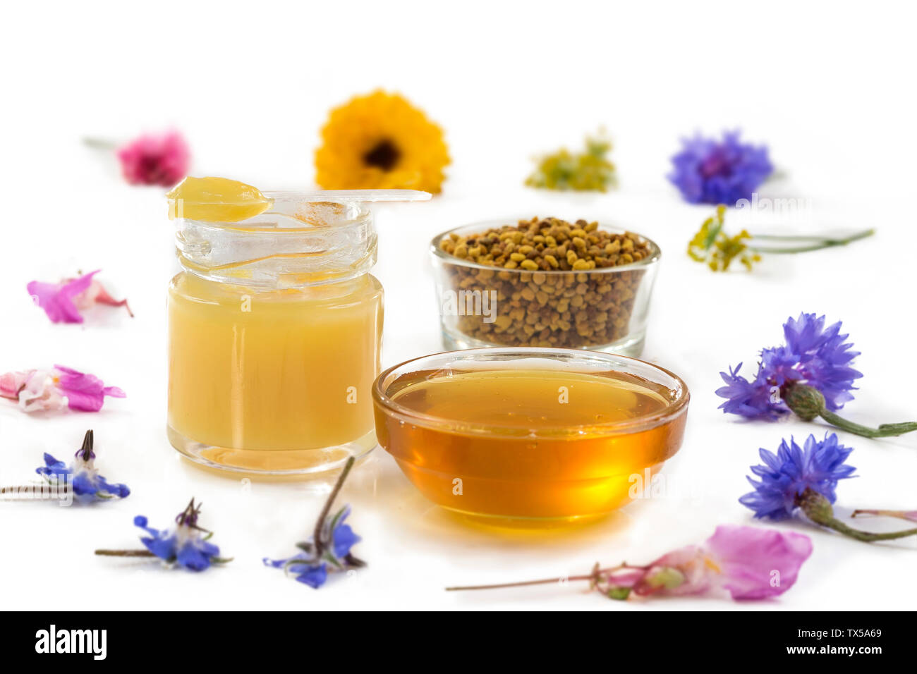 Variety of raw organic honey bee products board surrounded by flowers on white background Stock Photo