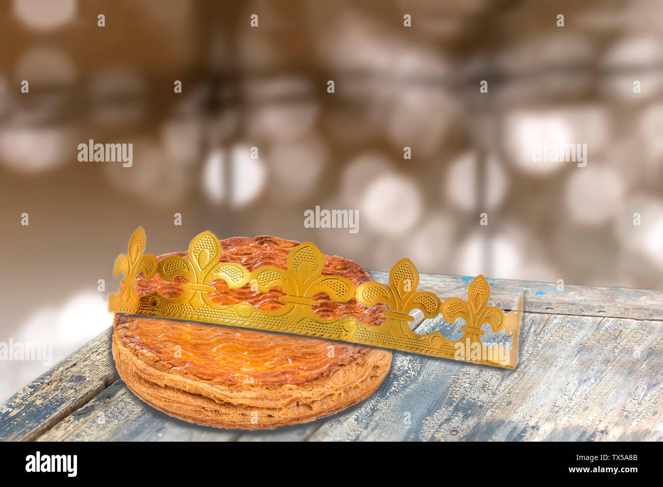 Galette des rois, french kingcake with a golden crown, on wooden table ,epiphany cake against blury light Stock Photo