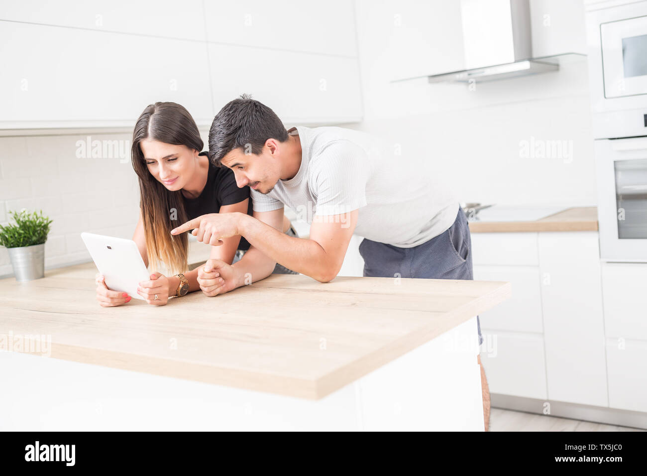 Young couple in home kitchen using tablet. Stock Photo