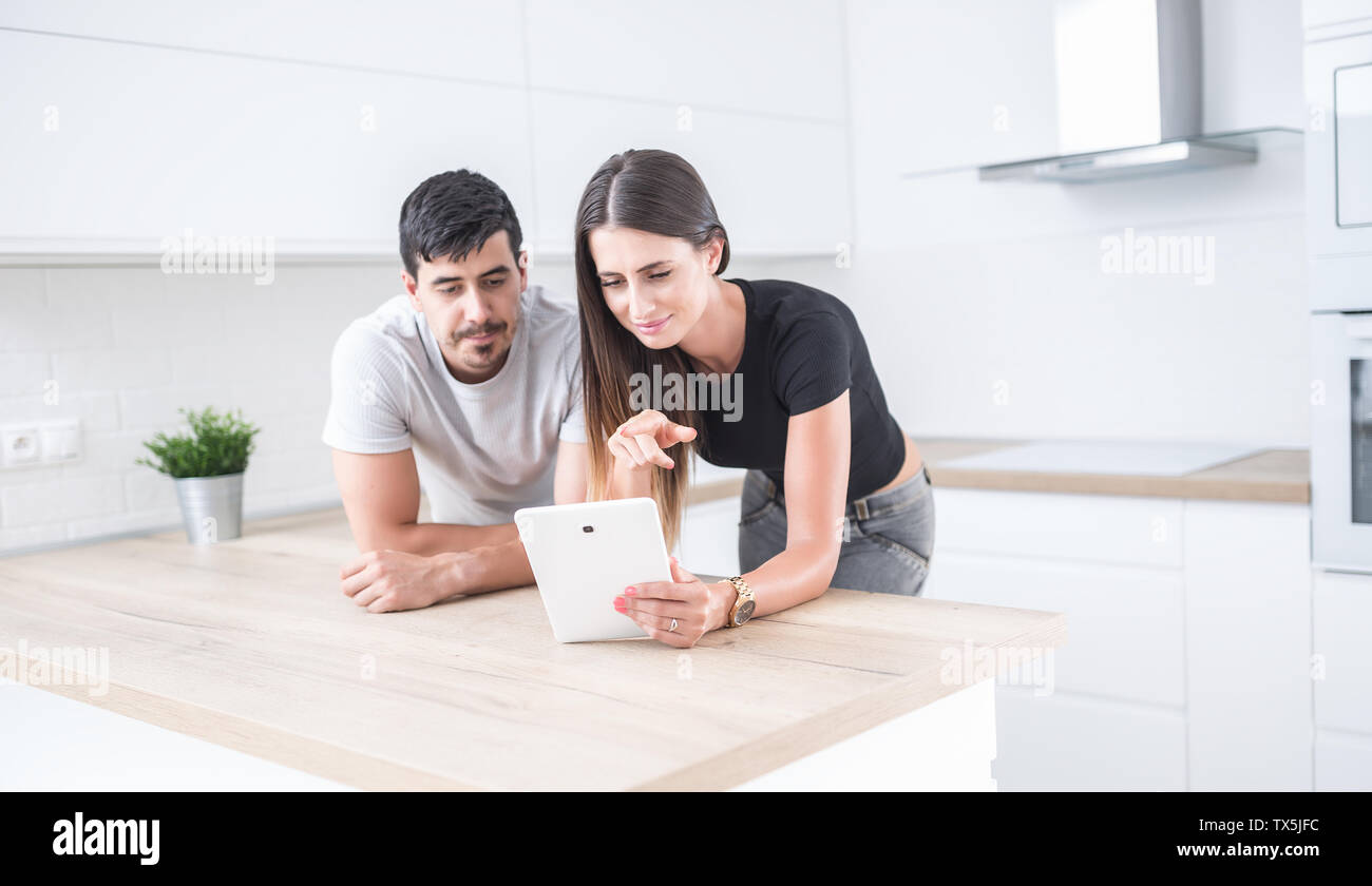 Young couple in home kitchen using tablet. Stock Photo