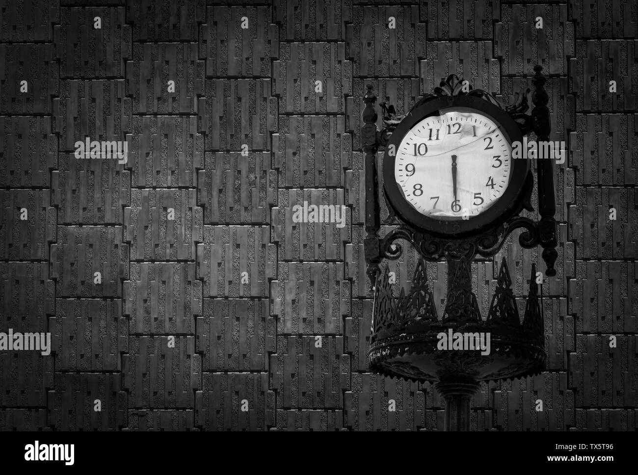Vintage analogue clock against black concrete wall Stock Photo
