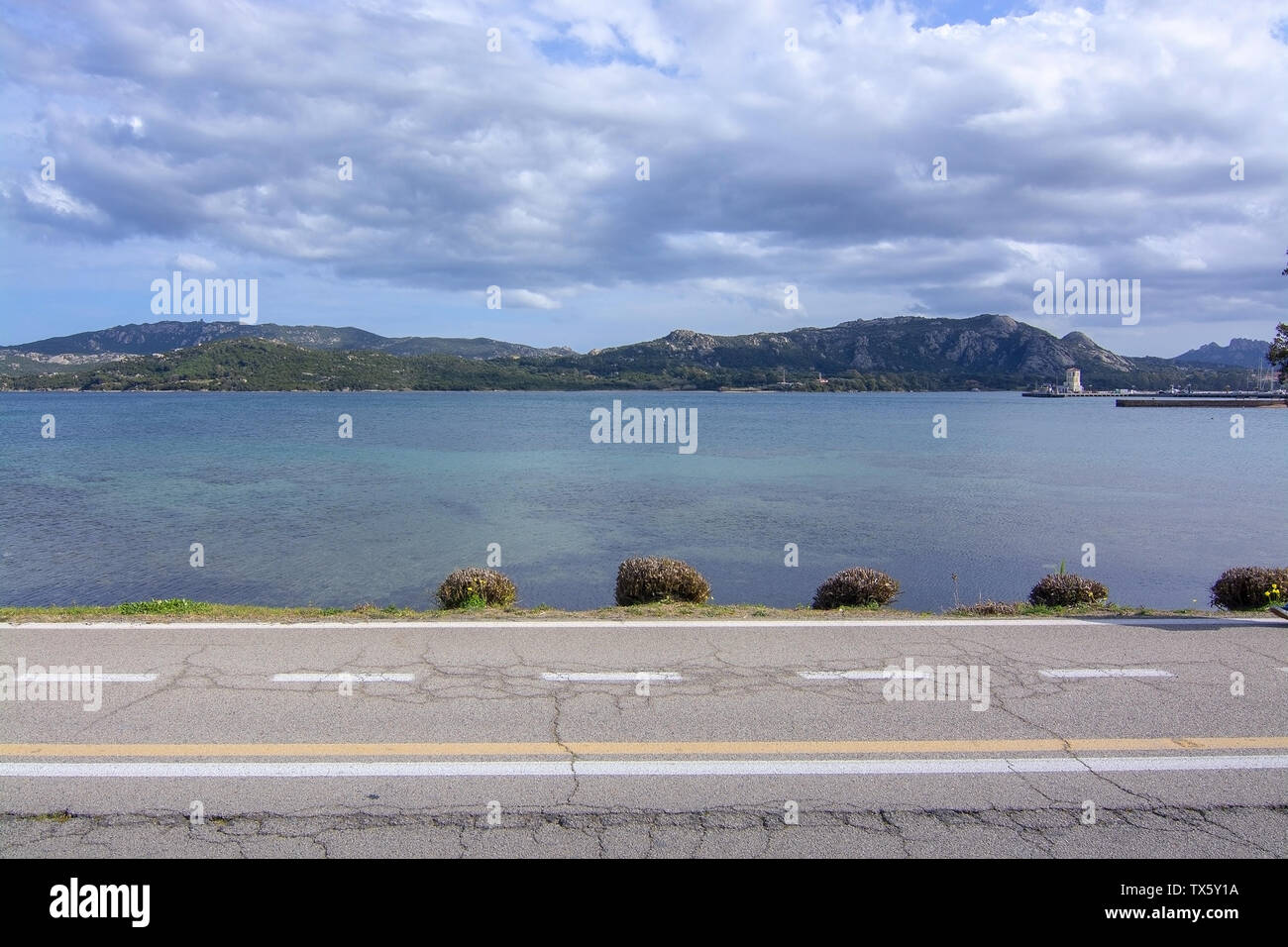 Asphalt countryroad crosses horizontal next to Mediterranean sea in Sardinia, Italy. Stock Photo
