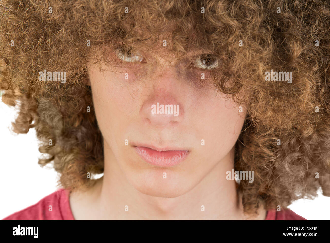 portrait of a young curly European man with a serious look looking at ...