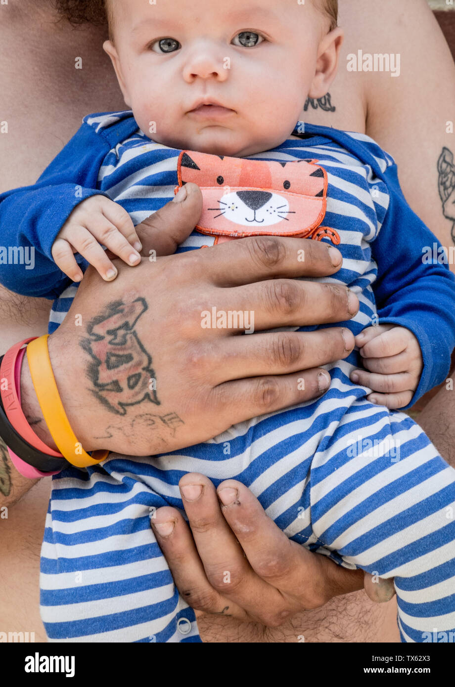 a father with tattoos holds his baby son in his arms Stock Photo - Alamy, image size:920x1390