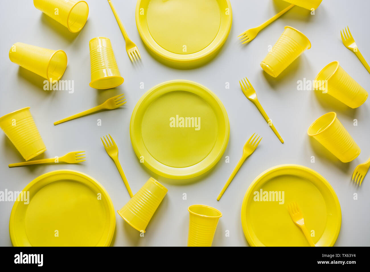 Single use yellow picnic utensils on grey. Environment, eco friendly, discarded, plastic garbage for recycle concept.Top view. Flat lay. Pattern. Stock Photo