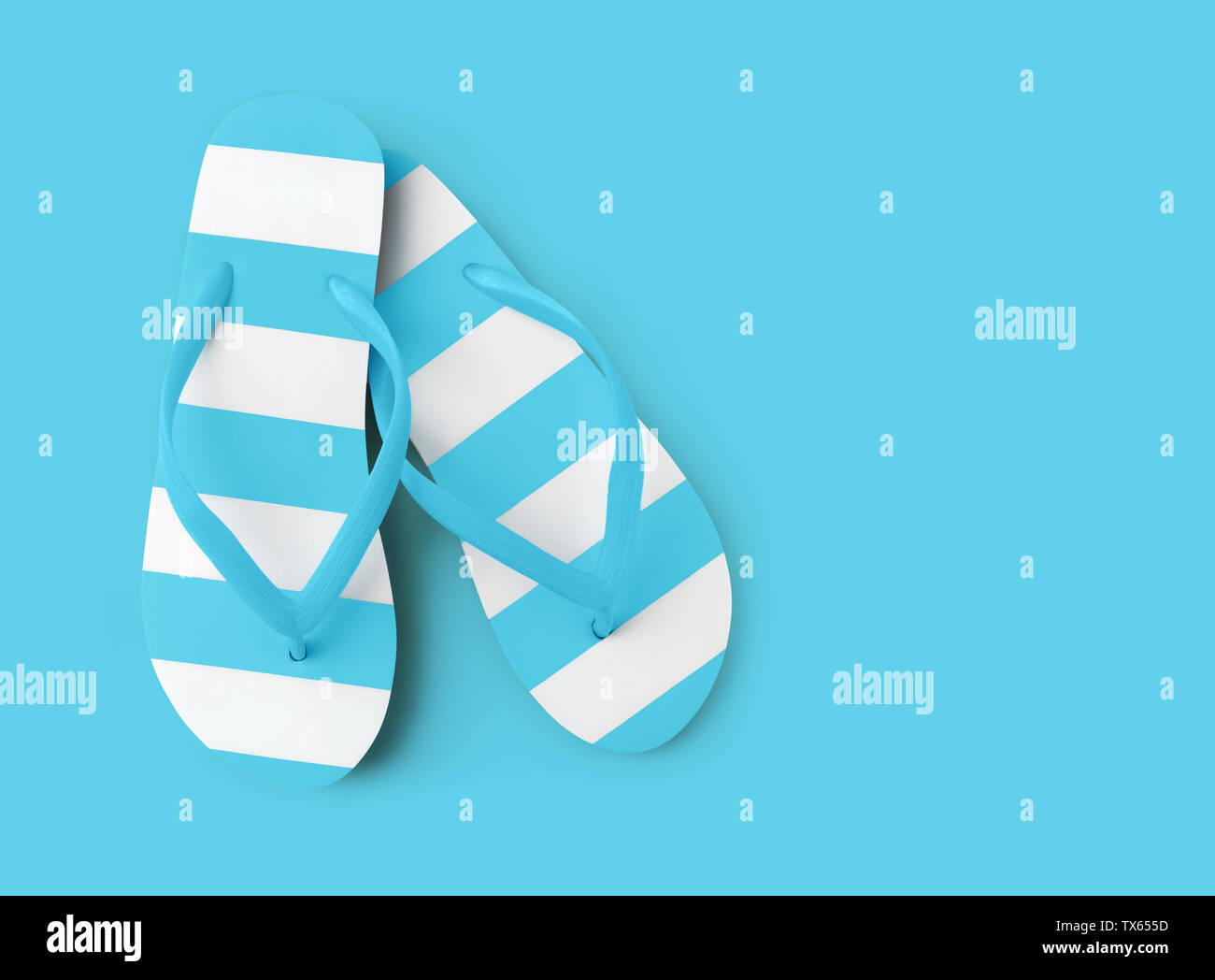 Top view of summer beach light blue flip flop on azure background sea ...
