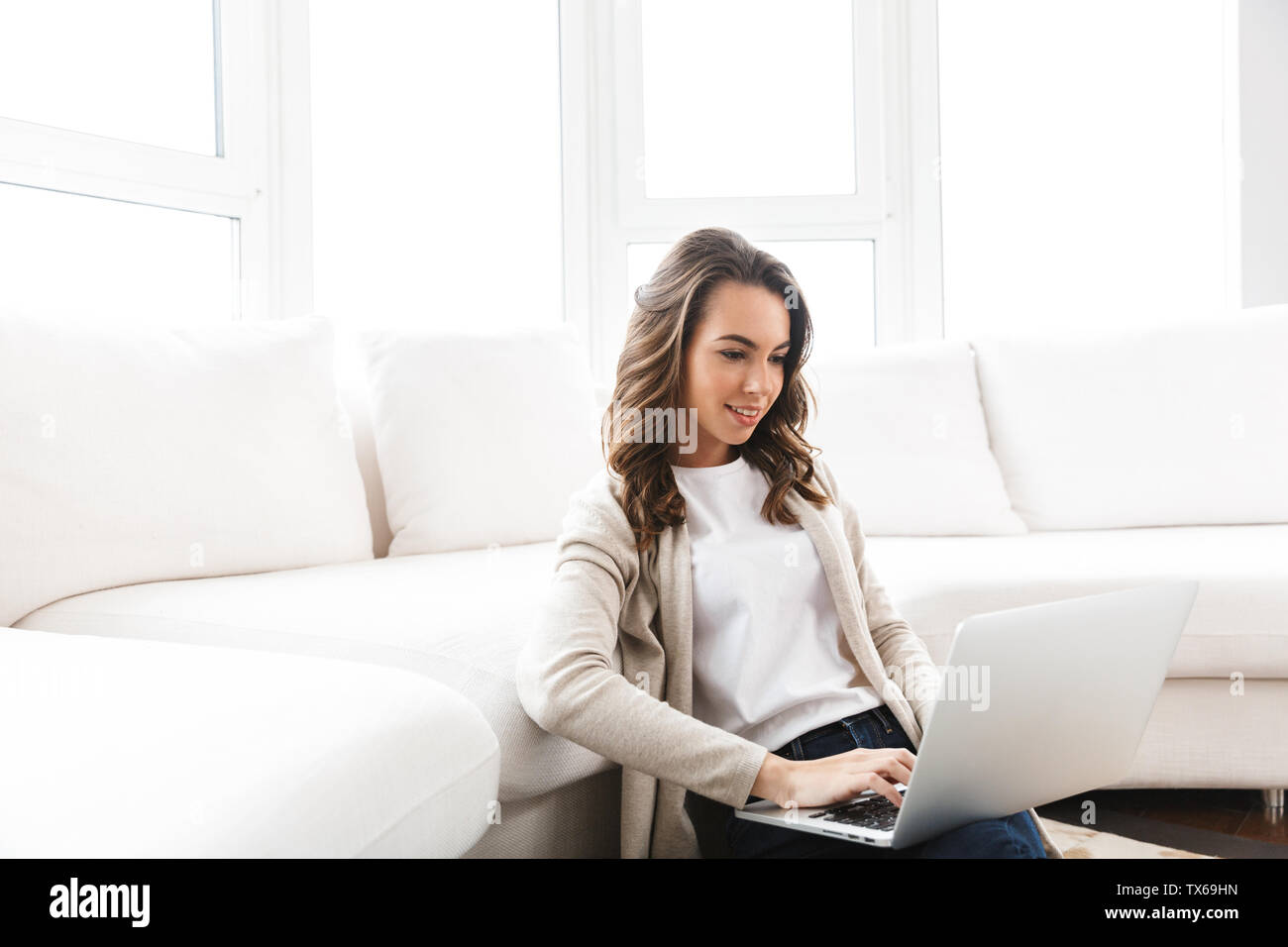 Beautiful young woman working on laptop computer while sitting at the ...