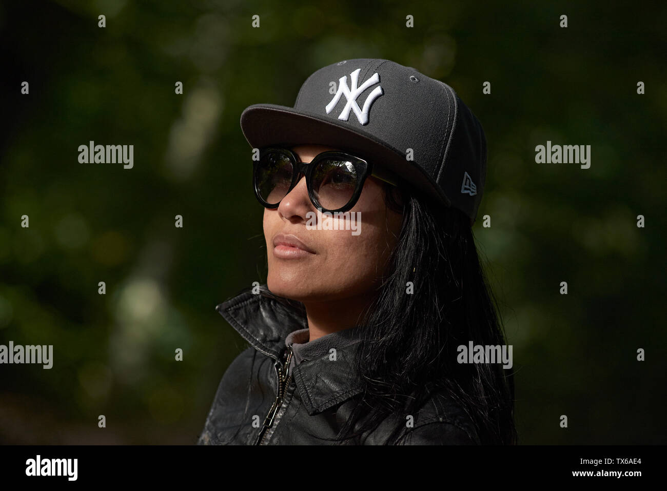 Portrait of woman wearing a black New Era New York hat in spring sunrise in the park Stock Photo - Alamy