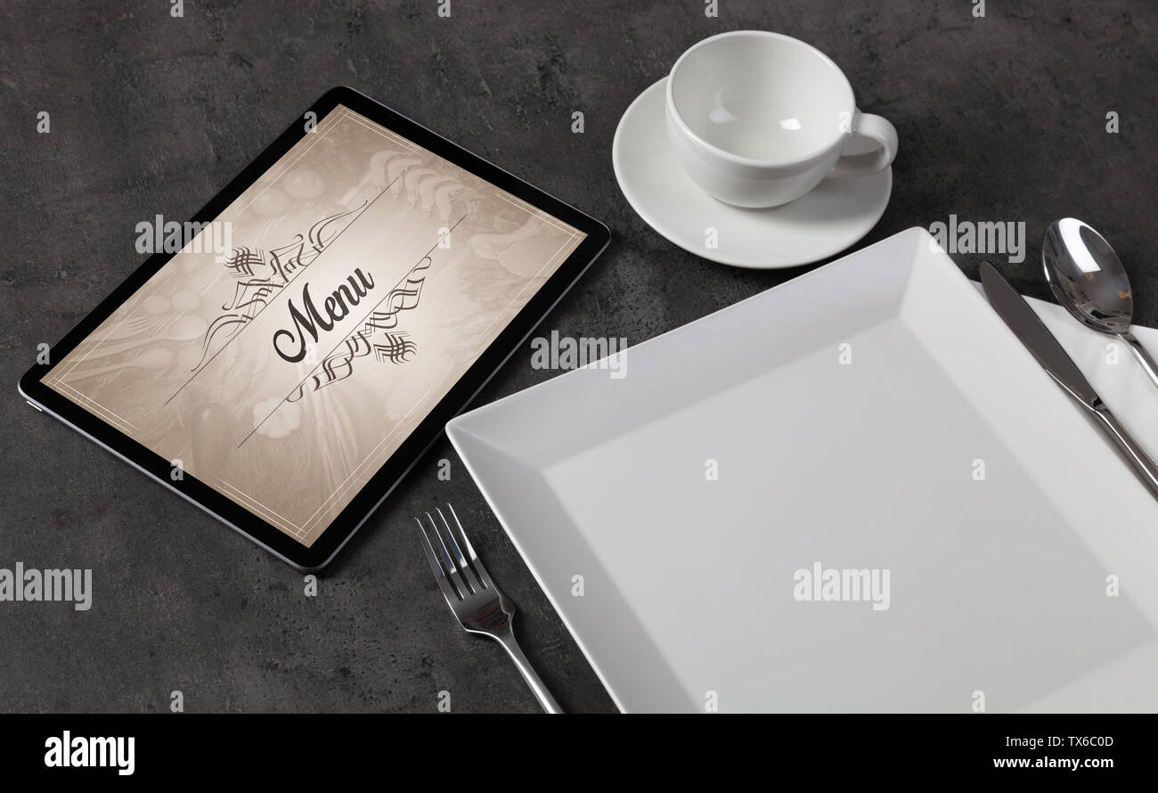 Tablet with stylish restaurant logo and laid table Stock Photo