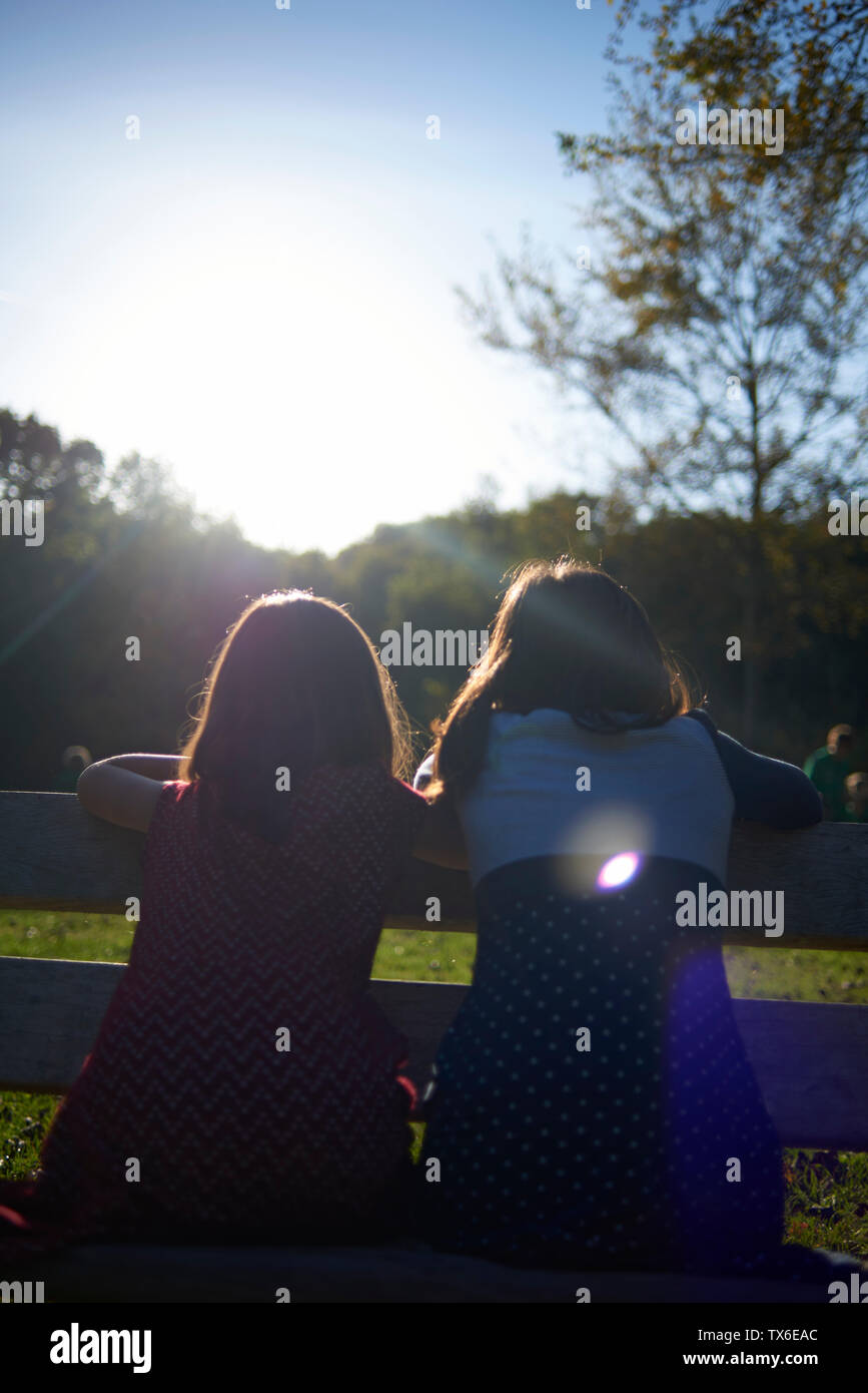 Two young girl holding hands on a fence whilst playing in the park in