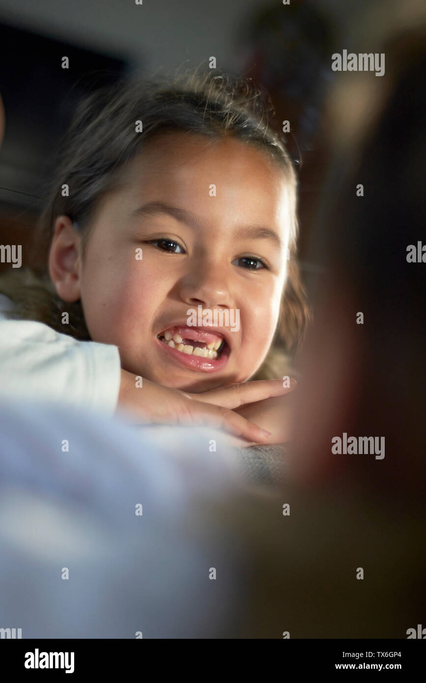 Cute little Asian girl looking in the mirror showing of the gap between