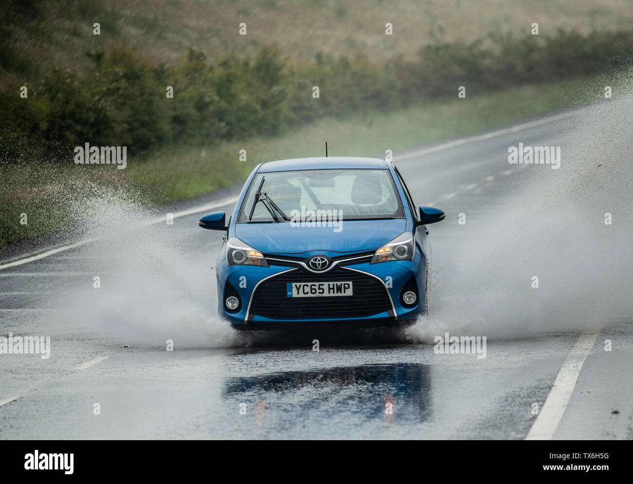 A car is driven through localised flooding near Leeming in Yorkshire, on what is expected to be the hottest day of the year, as thunderstorms could bring a month's worth of rain to parts of the UK, before the hottest temperatures of the year so far bring a balmy end to June. Stock Photo