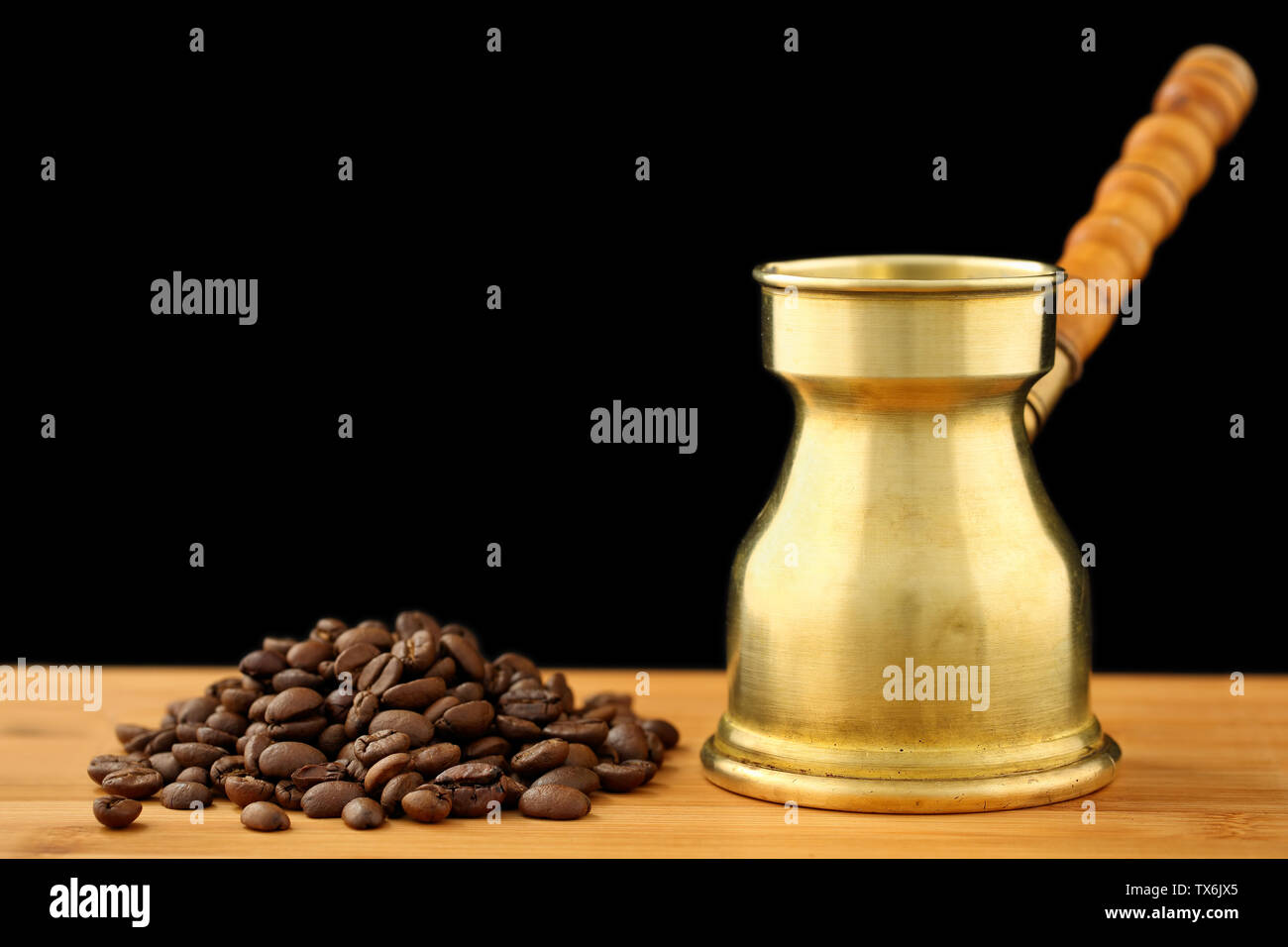 https://c8.alamy.com/comp/TX6JX5/old-vintage-brass-turkish-coffee-pot-dzhezve-with-carved-wooden-handle-and-a-pile-of-roasted-coffee-beans-on-a-wooden-table-against-black-backgroun-TX6JX5.jpg