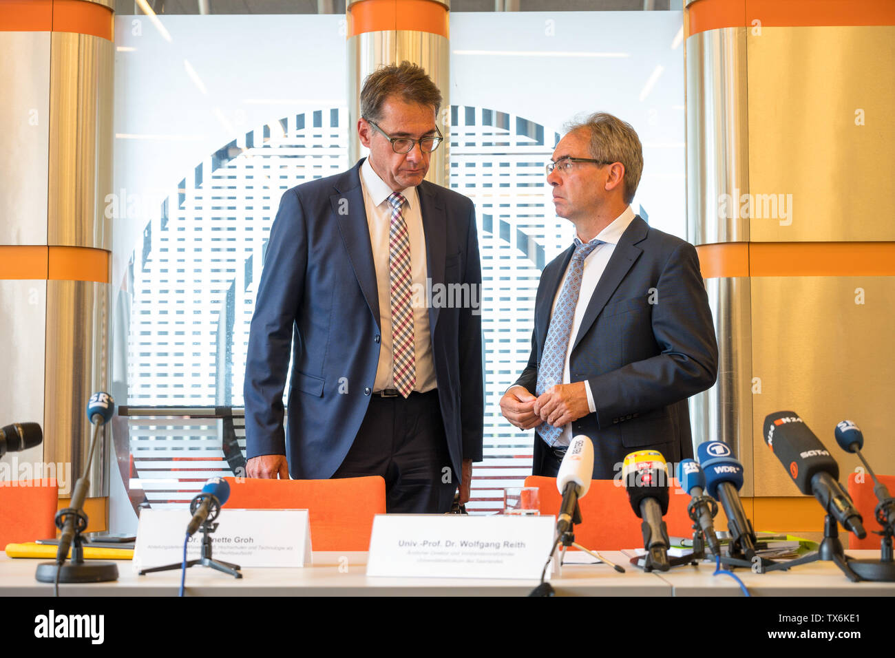 Homburg, Germany. 24th June, 2019. Wolfgang Reith (r), Medical Director of  the Saarland University Hospital, and Michael Görlinger, Senior Public  Prosecutor, speak to each other before a press conference. By 2014, an