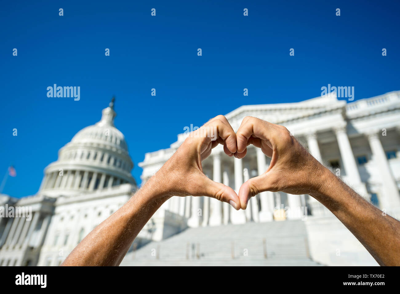 Happy fingers forming a hand heart on a bright sunny view of the Capitol Building in Washington, DC, USA Stock Photo