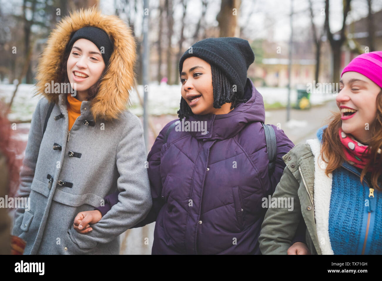 three girlfriends walking together in park – friendship, excursion, multiracial Stock Photo
