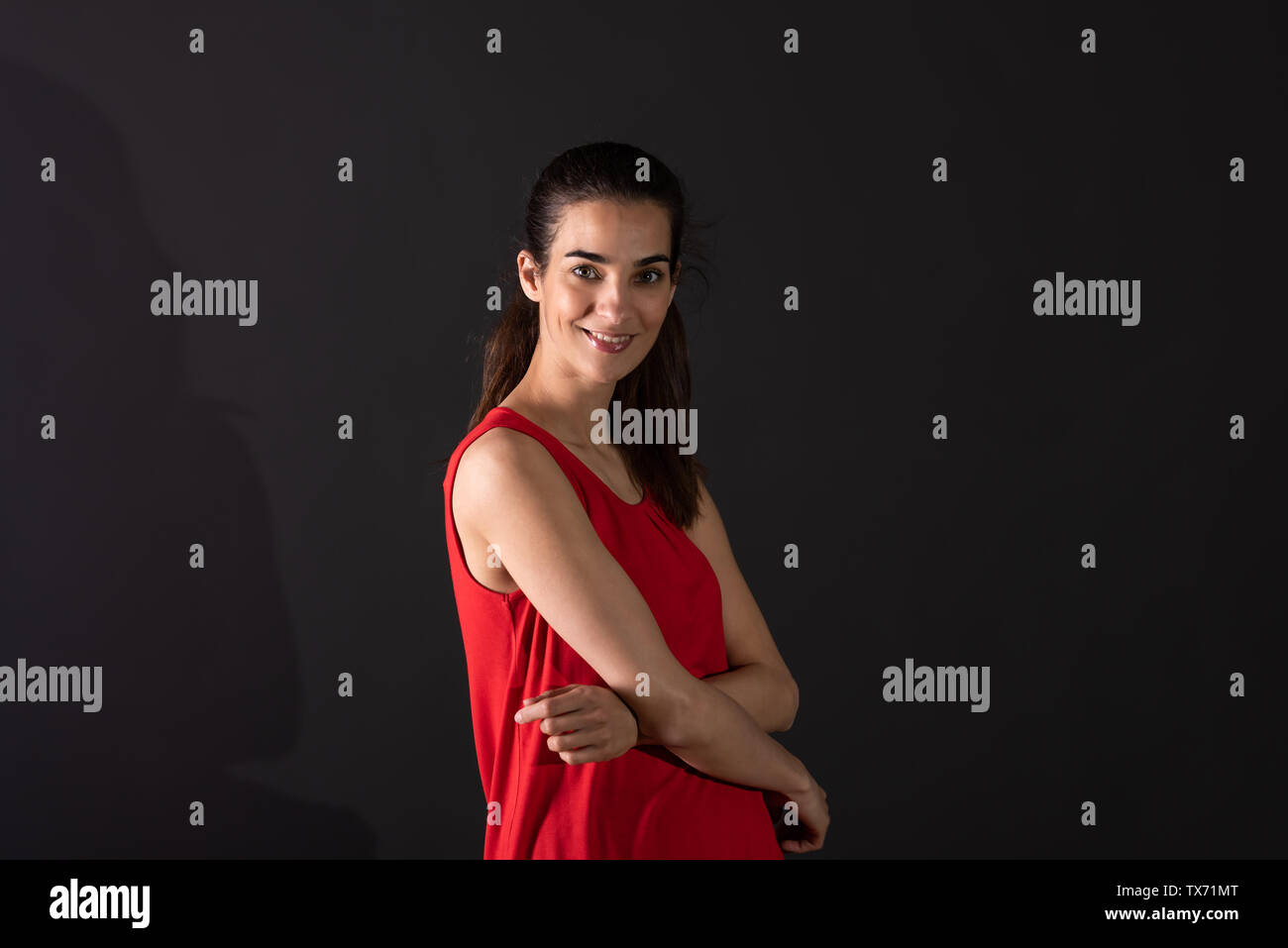 A beautiful smiling young woman in a red dress standing in front of a ...