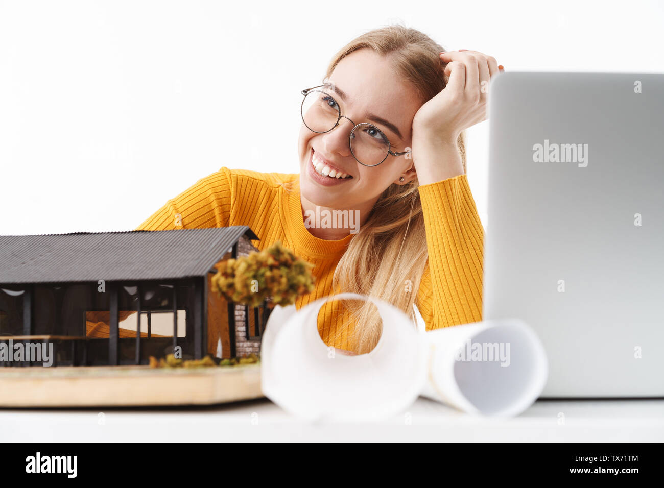 Beautiful young blonde woman architect standing isolated over white background, working on a new project at the desk with laptop Stock Photo