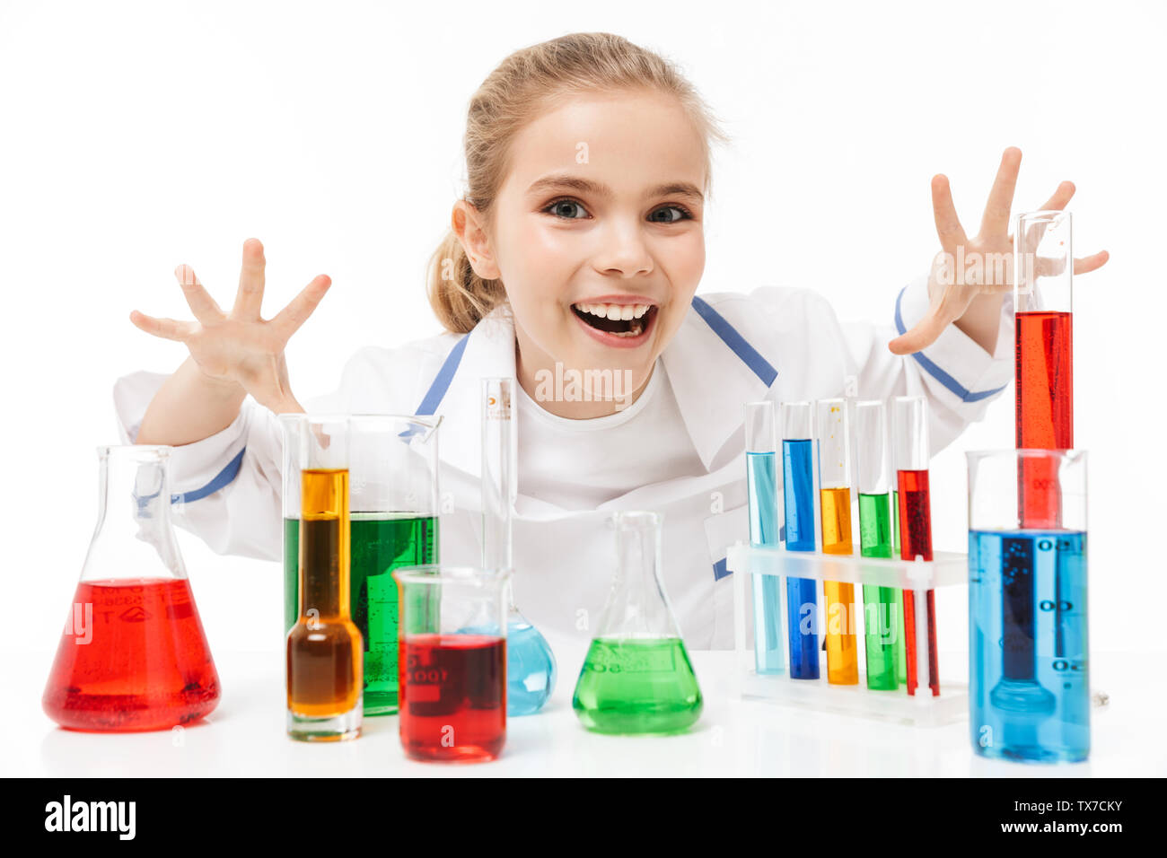Image of happy school girl in white laboratory coat making chemical