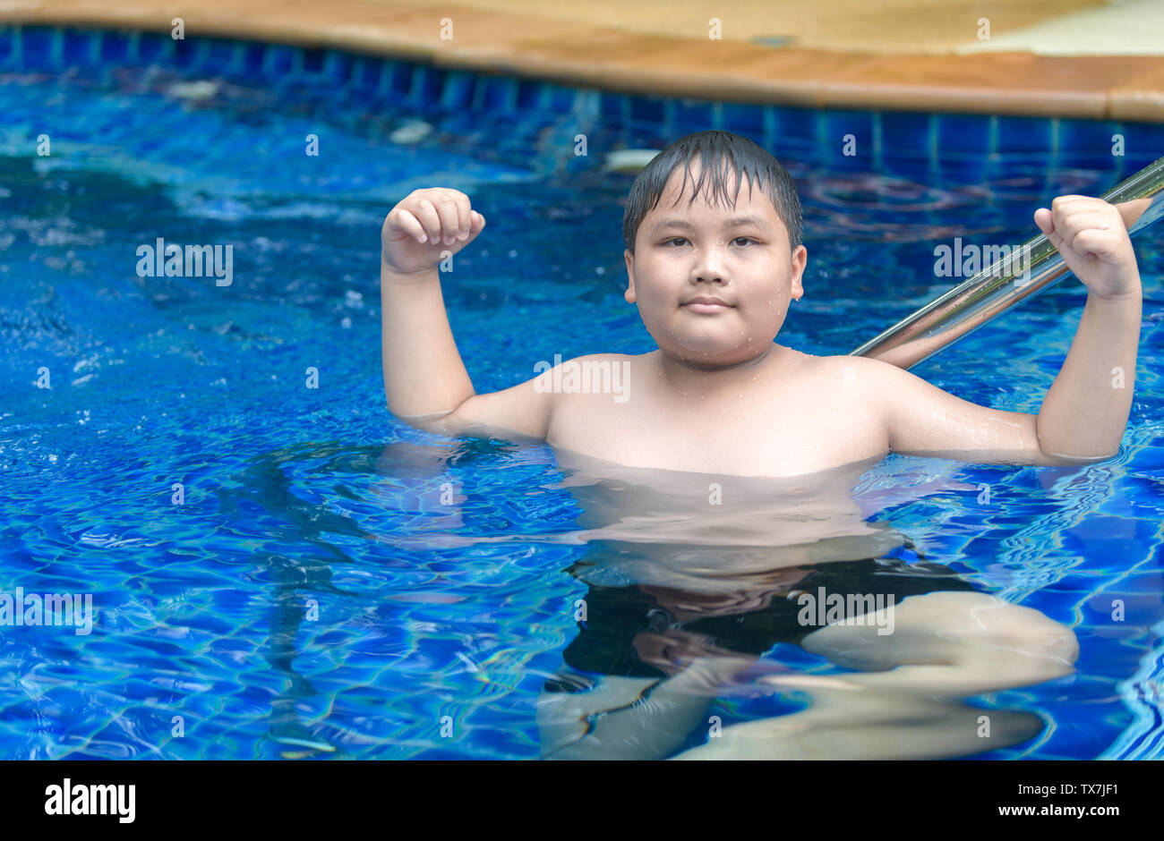 Obese fat boy show muscle in swimming pool, exercise and healthy