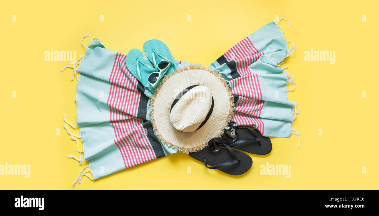 Outfit for beach tropical vacations, straw sun hat, towel, sun glasses on yellow. Summer vacations concept. Top view. Banner. Stock Photo