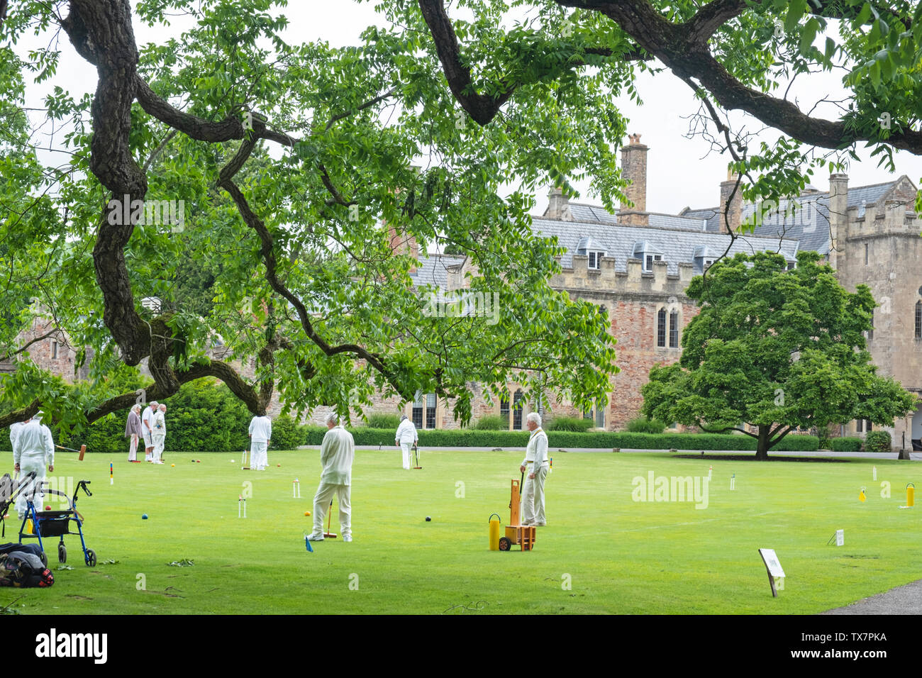 Wells, England – June 12, 2019: Senior team members of a local croquet club enjoy a game in the grounds of the Bishop’s Palace in the Somerset city Stock Photo