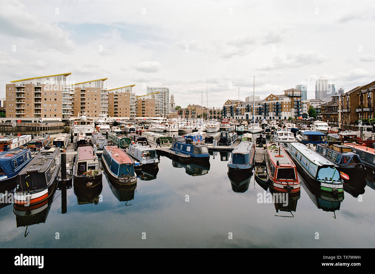 Narrowboats moored in Limehouse Basin in London's East End, looking east towards Canary Wharf and Limeouse church Stock Photo